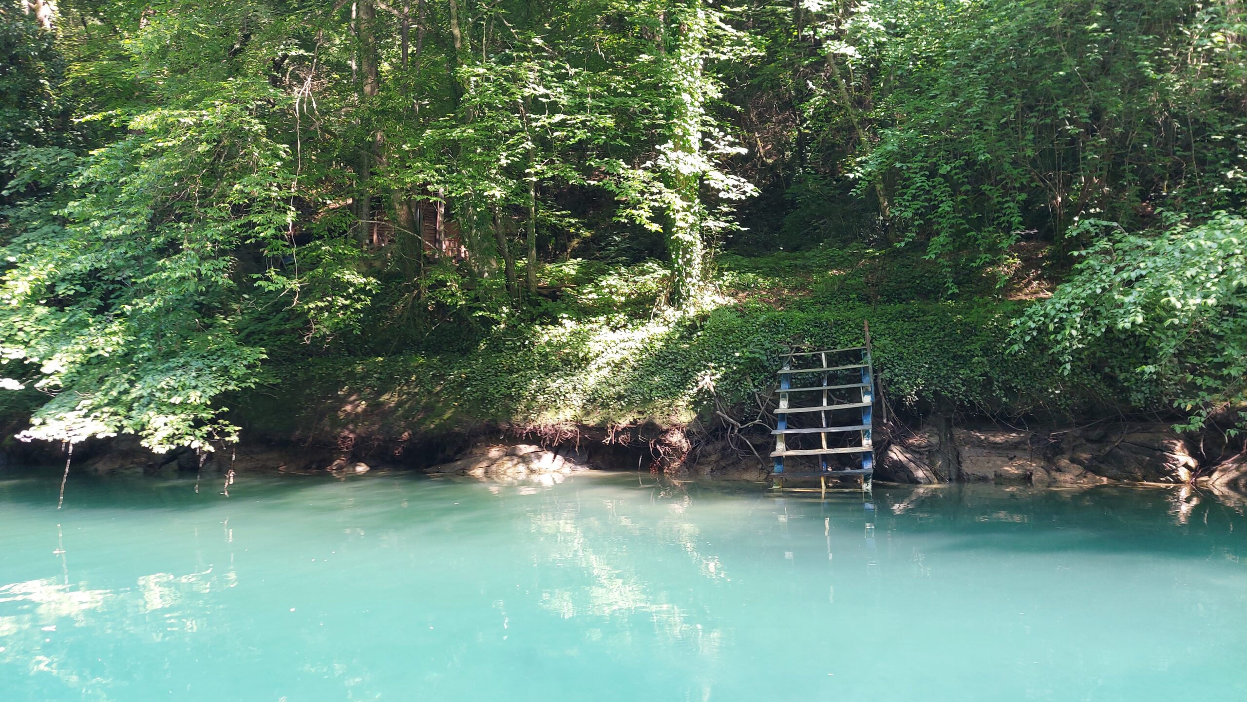 Das türkisfarbene Wasser des Treska Flusses im Matka Canyon mit dem Eingang zur Vrelo Höhle im Hintergrund